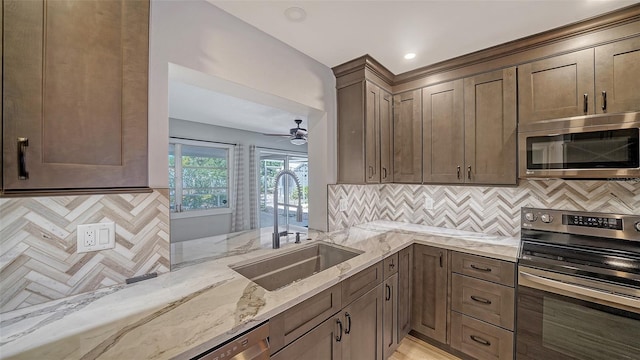 5706 10th Avenue Dr W, Bradenton, FL 34209 - kitchen featuring stainless steel appliances, a sink, light stone countertops, backsplash, and a ceiling fan