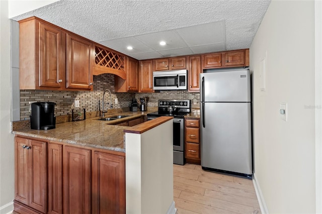 kitchen featuring appliances with stainless steel finishes, a sink, light wood-style floors, tasteful backsplash, and recessed lighting