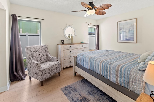 bedroom with light wood finished floors, a textured ceiling, and a ceiling fan