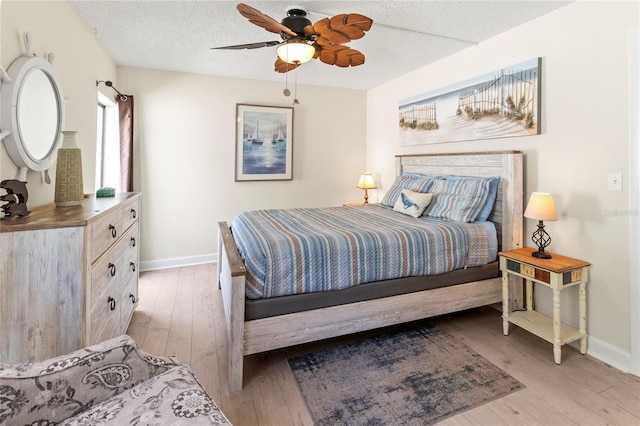bedroom featuring light wood finished floors, baseboards, a textured ceiling, and ceiling fan