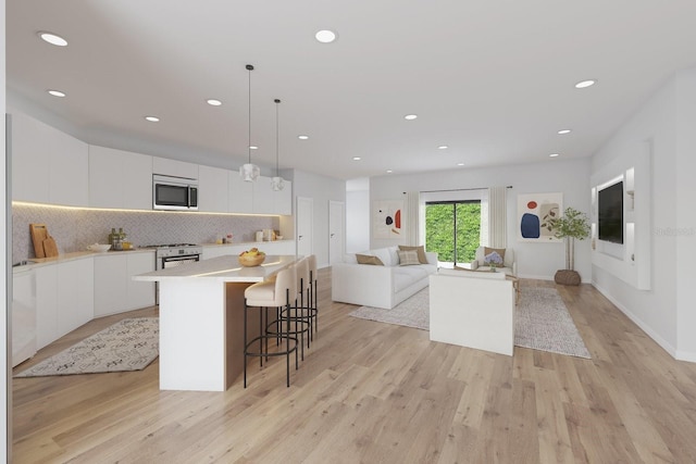kitchen featuring appliances with stainless steel finishes, modern cabinets, white cabinetry, light wood-style floors, and a kitchen breakfast bar