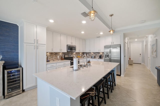 910 Tidewater Shores Loop Unit 103, Bradenton, FL 34208 - kitchen featuring appliances with stainless steel finishes, wine cooler, tasteful backsplash, a kitchen bar, and white cabinetry