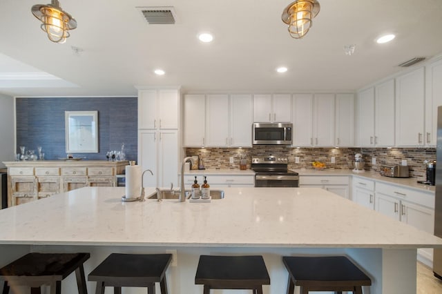 910 Tidewater Shores Loop Unit 103, Bradenton, FL 34208 - kitchen with stainless steel appliances, a sink, backsplash, white cabinets, and recessed lighting