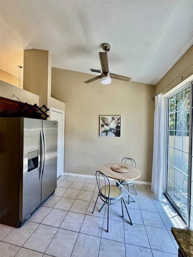 dining area with light tile patterned floors, a textured ceiling, a ceiling fan, and baseboards