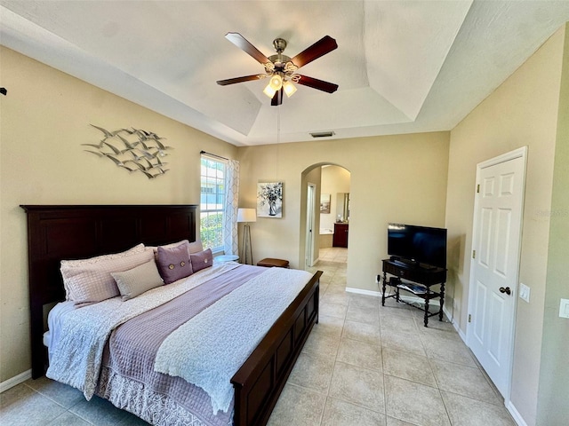 bedroom with a raised ceiling, arched walkways, baseboards, and ceiling fan