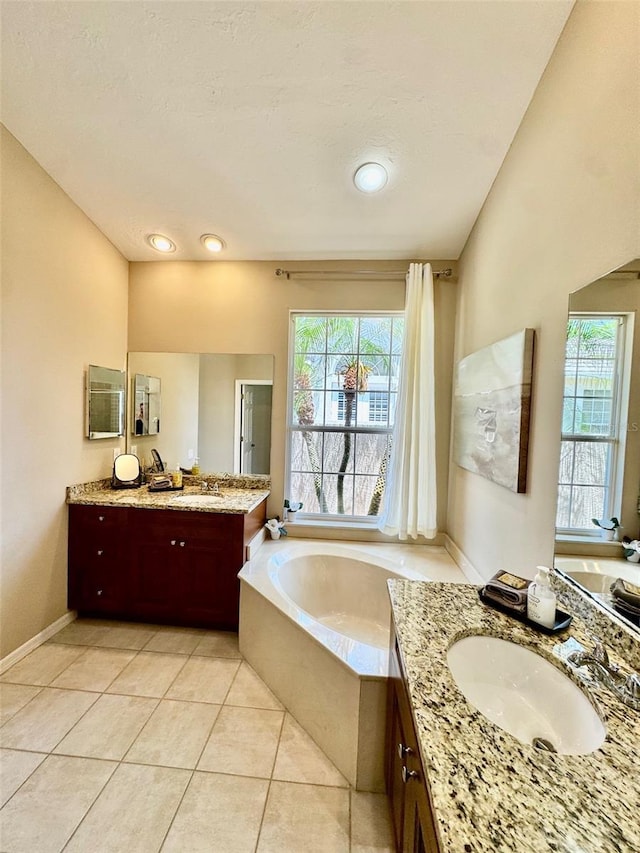 bathroom with a bath, two vanities, and tile patterned floors
