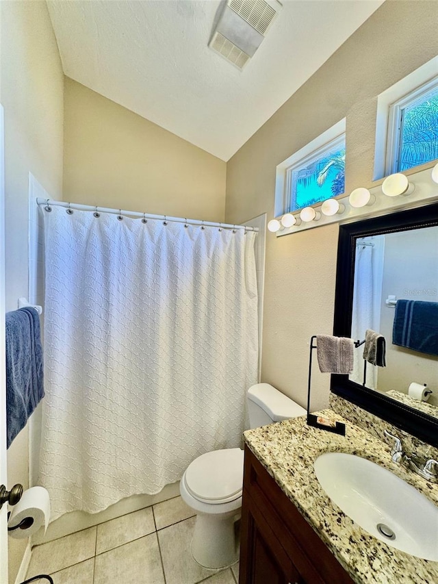 bathroom featuring toilet, tile patterned flooring, vanity, vaulted ceiling, and healthy amount of natural light