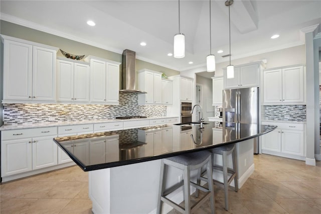 kitchen with wall chimney exhaust hood, a sink, decorative backsplash, stainless steel appliances, and an island with sink