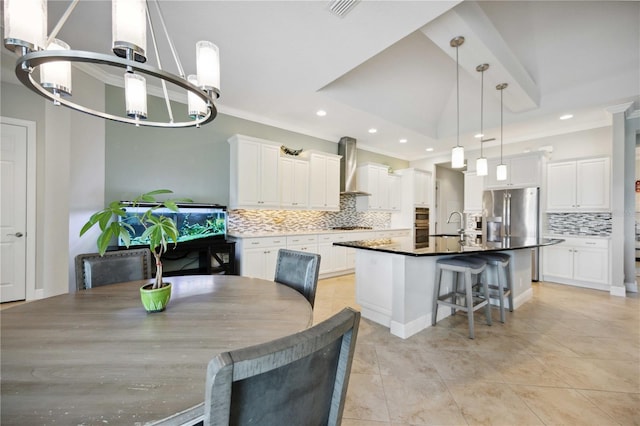 kitchen with wall chimney range hood, tasteful backsplash, a chandelier, white cabinets, and recessed lighting