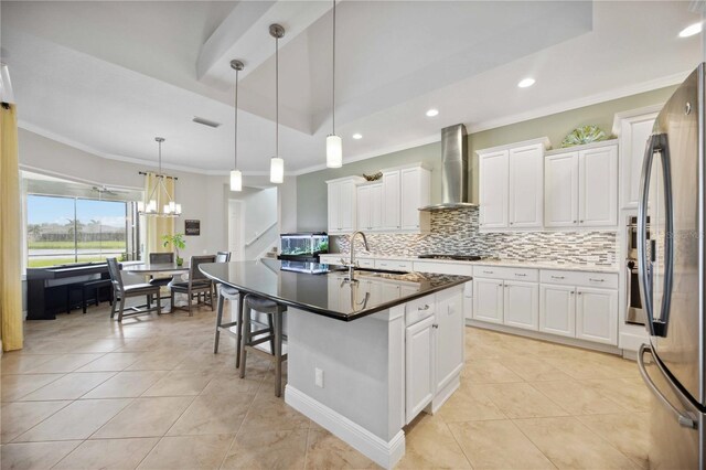 kitchen with wall chimney range hood, appliances with stainless steel finishes, ornamental molding, tasteful backsplash, and a sink
