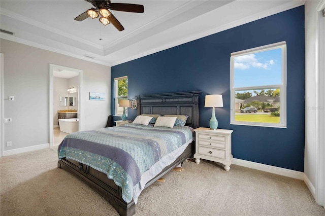 carpeted bedroom with baseboards, a tray ceiling, connected bathroom, ceiling fan, and crown molding