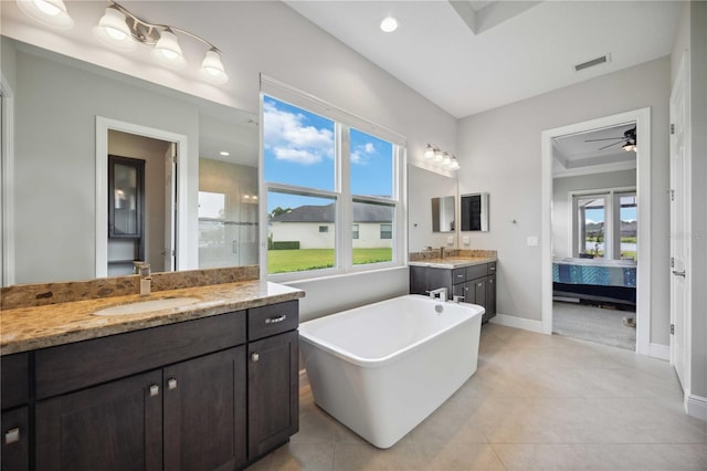 bathroom featuring ensuite bath, baseboards, two vanities, a freestanding tub, and tile patterned flooring