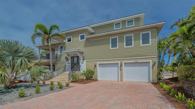 view of front facade with an attached garage, decorative driveway, and a balcony