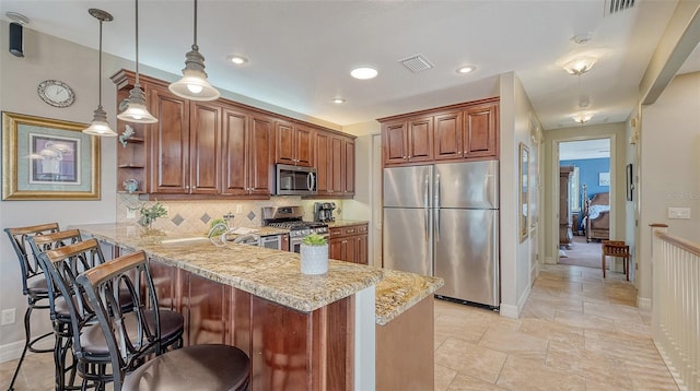 kitchen with appliances with stainless steel finishes, a peninsula, light stone countertops, tasteful backsplash, and a kitchen bar