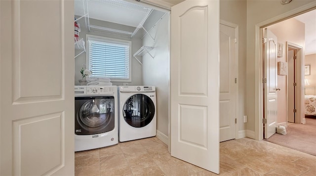 laundry room with washer and dryer, light stone finish flooring, and baseboards