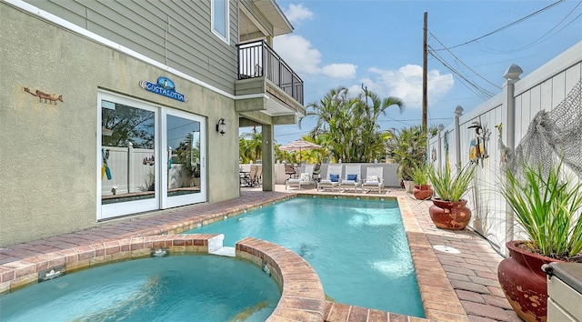 view of swimming pool featuring a pool with connected hot tub, a patio, and fence