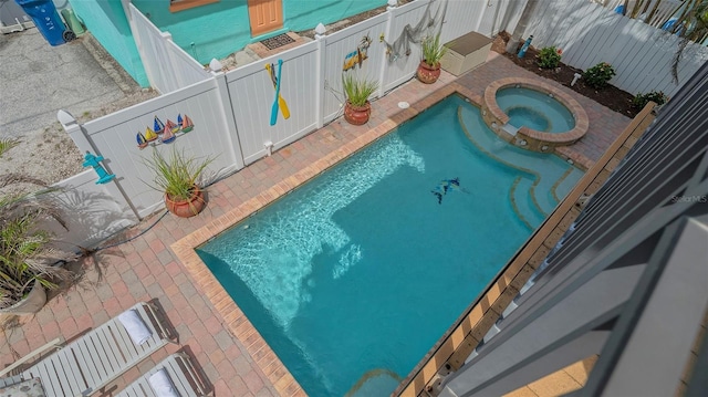 view of pool featuring a patio, a fenced backyard, and a pool with connected hot tub