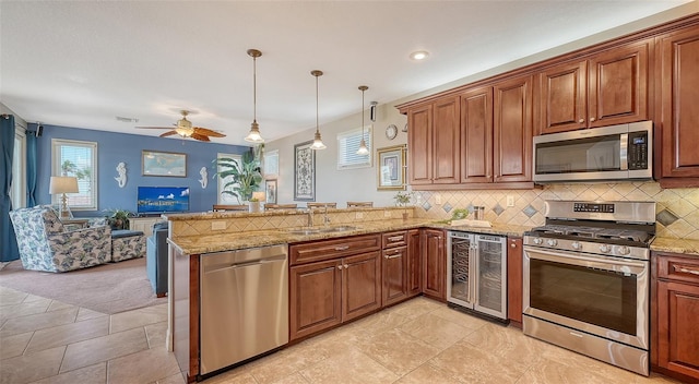 kitchen with stainless steel appliances, a sink, a peninsula, beverage cooler, and open floor plan