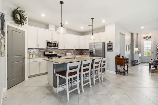 5165 Coral Reef Way, Bradenton, FL 34211 - kitchen with stainless steel appliances, a sink, backsplash, light stone countertops, and a center island with sink