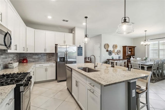 5165 Coral Reef Way, Bradenton, FL 34211 - kitchen with a sink, appliances with stainless steel finishes, light tile patterned floors, decorative backsplash, and a kitchen breakfast bar