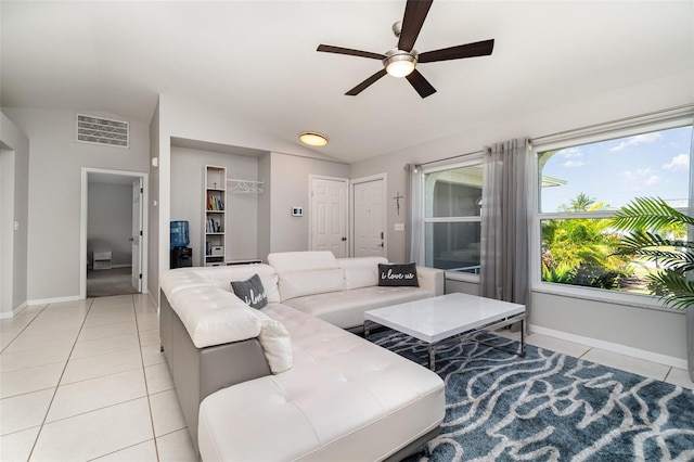 living room featuring a ceiling fan, vaulted ceiling, light tile patterned flooring, and baseboards