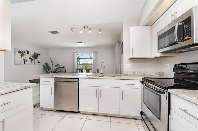 kitchen with appliances with stainless steel finishes, a sink, light tile patterned floors, white cabinetry, and a peninsula