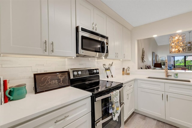 5632 Ashton Lake Dr Unit 5632, Sarasota, FL 34231 - kitchen featuring stainless steel appliances, a sink, white cabinets, backsplash, and a chandelier