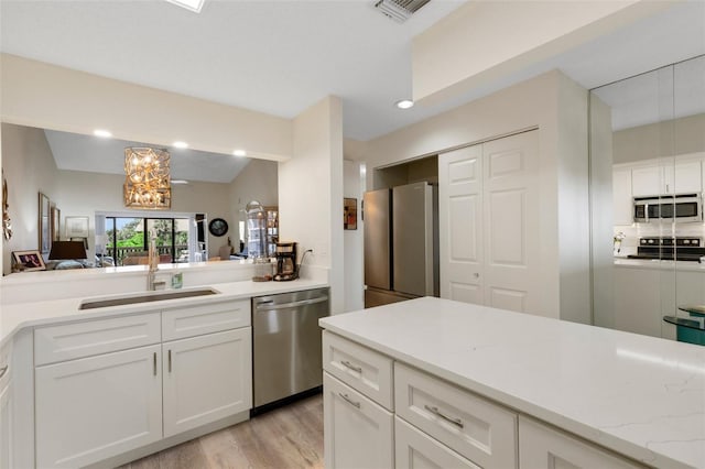 5632 Ashton Lake Dr Unit 5632, Sarasota, FL 34231 - kitchen featuring appliances with stainless steel finishes, a sink, white cabinets, light wood-style flooring, and a chandelier