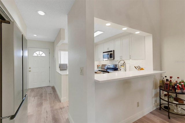 5632 Ashton Lake Dr Unit 5632, Sarasota, FL 34231 - kitchen featuring appliances with stainless steel finishes, light wood finished floors, white cabinets, tasteful backsplash, and light countertops