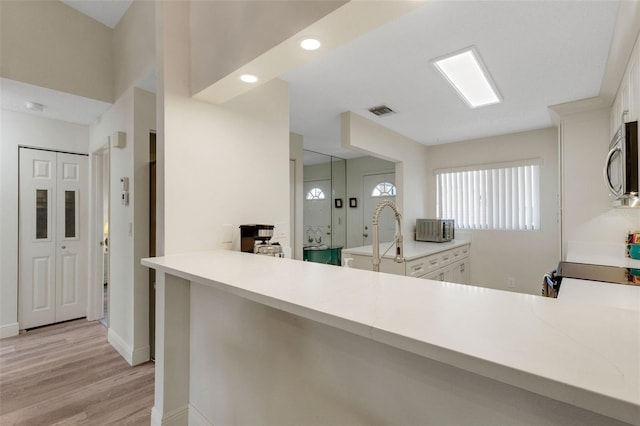 5632 Ashton Lake Dr Unit 5632, Sarasota, FL 34231 - kitchen featuring stainless steel microwave, light wood-type flooring, light countertops, white cabinetry, and recessed lighting
