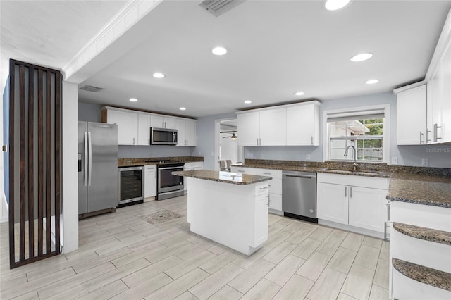 3616 Stardust Pl, Sarasota, FL 34232 - kitchen featuring stainless steel appliances, beverage cooler, a sink, white cabinets, and dark stone countertops