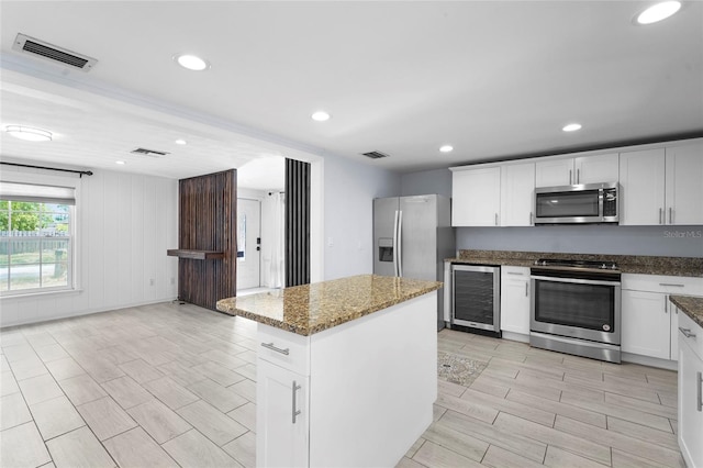 3616 Stardust Pl, Sarasota, FL 34232 - kitchen featuring stainless steel appliances, wine cooler, dark stone countertops, a kitchen island, and white cabinets