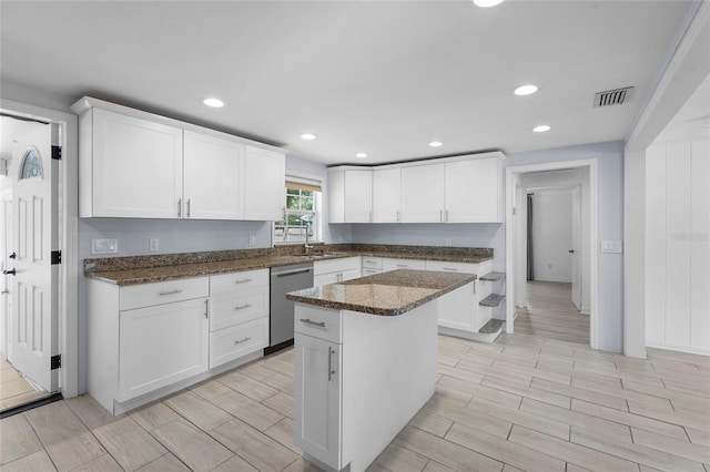 3616 Stardust Pl, Sarasota, FL 34232 - kitchen with dishwasher, wood tiled floors, white cabinetry, a sink, and dark stone counters