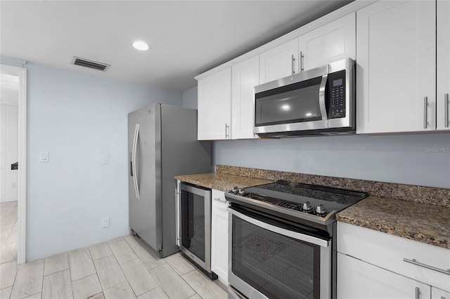 3616 Stardust Pl, Sarasota, FL 34232 - kitchen featuring stainless steel appliances, beverage cooler, white cabinetry, recessed lighting, and dark stone countertops