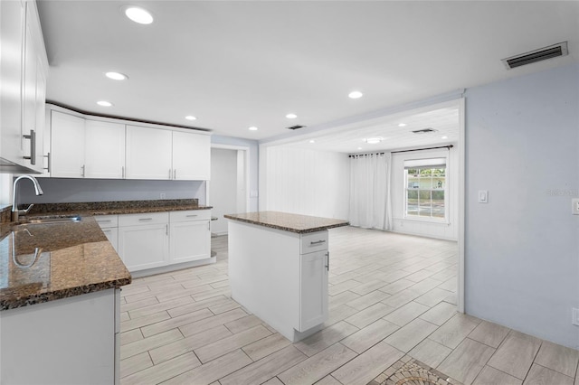 3616 Stardust Pl, Sarasota, FL 34232 - kitchen with a sink, white cabinetry, recessed lighting, a center island, and dark stone counters