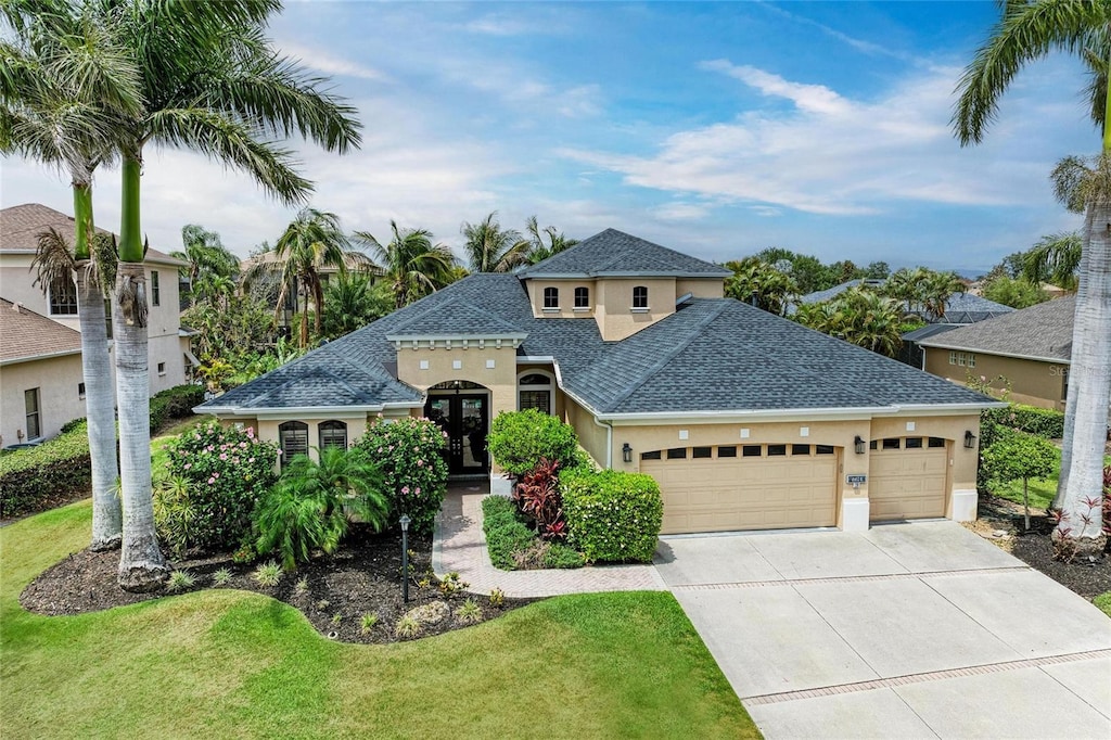 6674 Coopers Hawk Ct, Lakewood Ranch, FL 34202 - view of front of home with roof with shingles, a garage, stucco siding, concrete driveway, and a front lawn