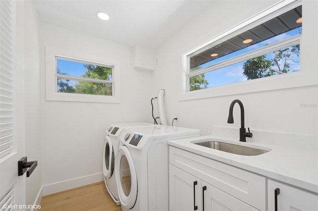 2655 Bay St, Sarasota, FL 34237 - washroom with light wood finished floors, a sink, cabinet space, washer and clothes dryer, and baseboards