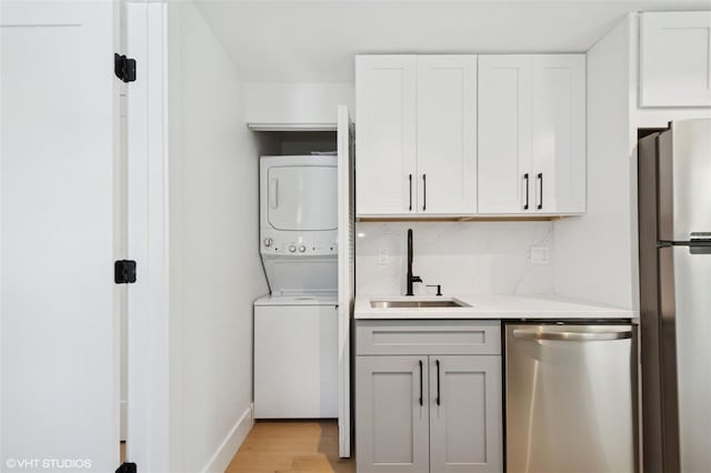 2655 Bay St, Sarasota, FL 34237 - laundry area featuring a sink, stacked washer and clothes dryer, baseboards, and light wood-style floors