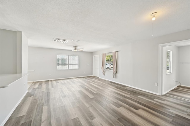 unfurnished living room featuring wood finished floors, a ceiling fan, baseboards, and a textured ceiling