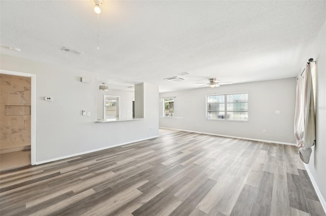 unfurnished living room with a ceiling fan, wood finished floors, a textured ceiling, and baseboards