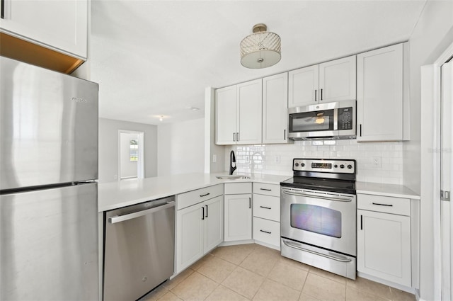kitchen featuring appliances with stainless steel finishes, a sink, light countertops, decorative backsplash, and white cabinetry