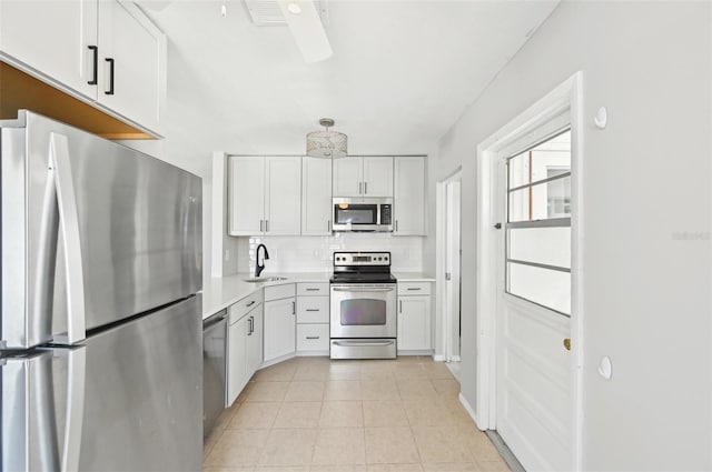 kitchen featuring appliances with stainless steel finishes, a sink, backsplash, light countertops, and white cabinets