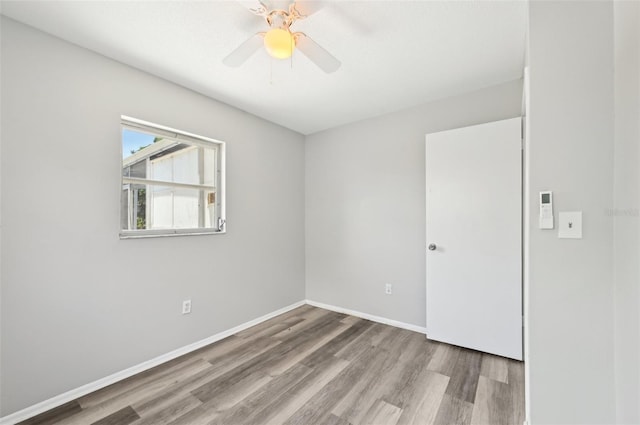 unfurnished room with wood finished floors, ceiling fan, and baseboards