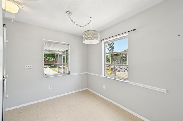 empty room featuring plenty of natural light, baseboards, a textured ceiling, and ceiling fan