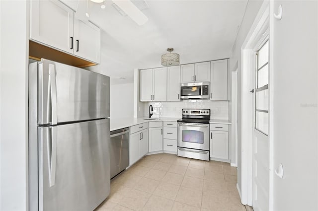 kitchen featuring appliances with stainless steel finishes, decorative backsplash, a sink, light countertops, and light tile patterned flooring