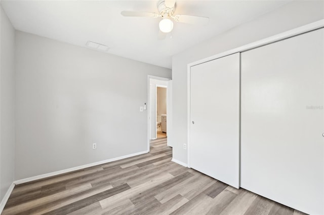 unfurnished bedroom featuring wood finished floors, a closet, baseboards, and ceiling fan