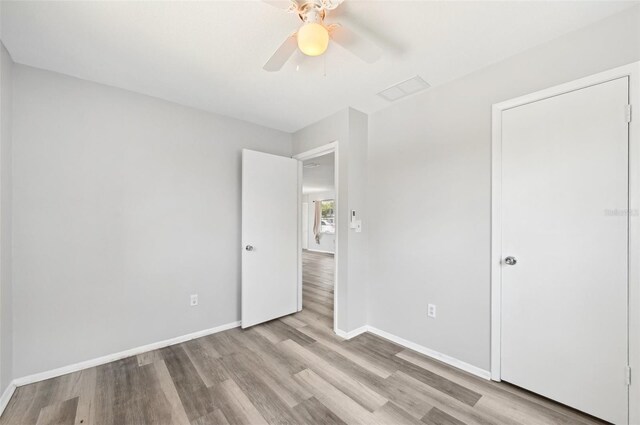 unfurnished bedroom featuring wood finished floors, baseboards, and a ceiling fan