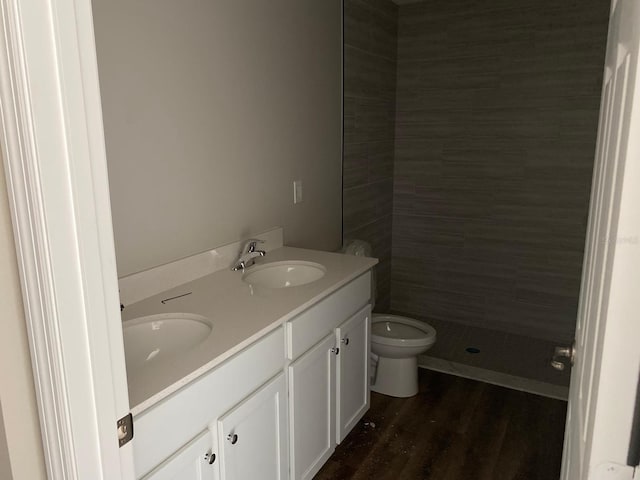 bathroom featuring a stall shower, wood finished floors, double vanity, and toilet