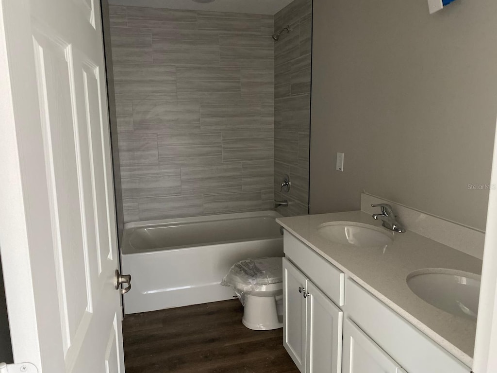 full bath featuring shower / washtub combination, double vanity, toilet, and wood finished floors