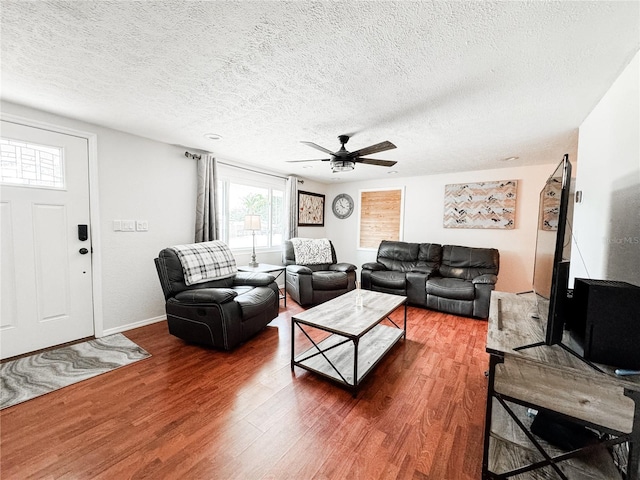living room with wood finished floors, a textured ceiling, a ceiling fan, and baseboards